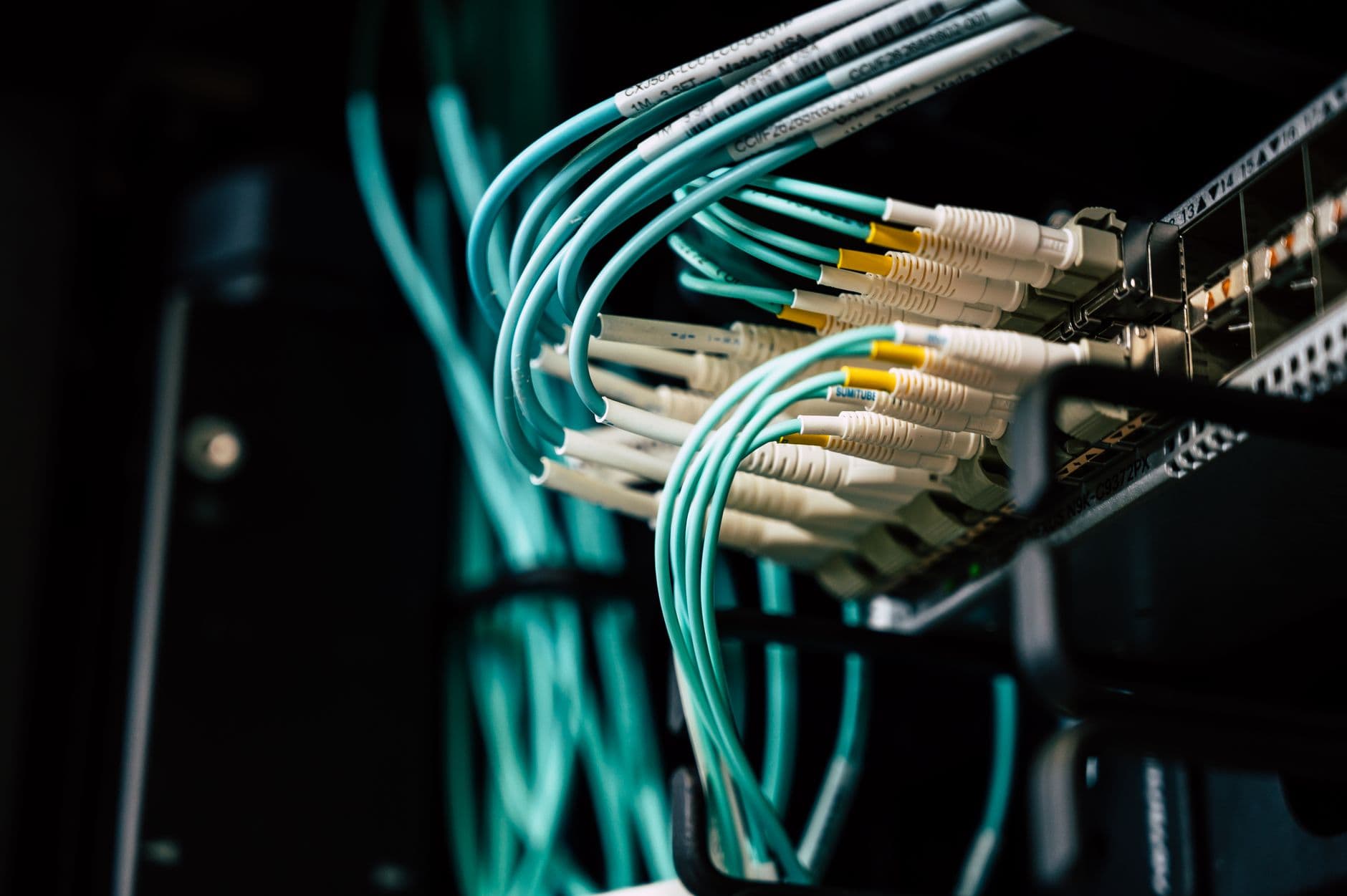 Technician connecting network cables on a switch rack
