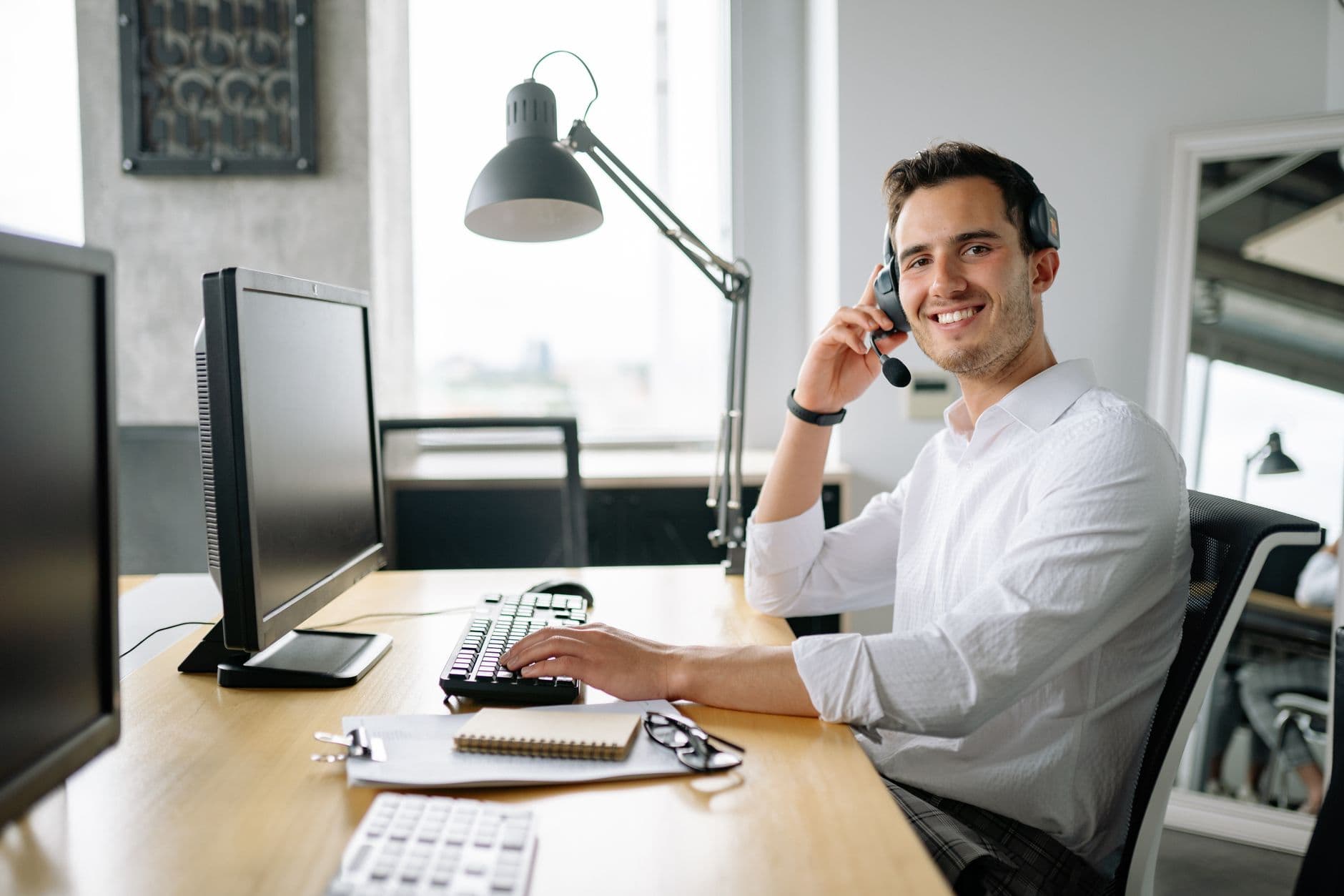 Professional taking a call on a headset at a computer in the office