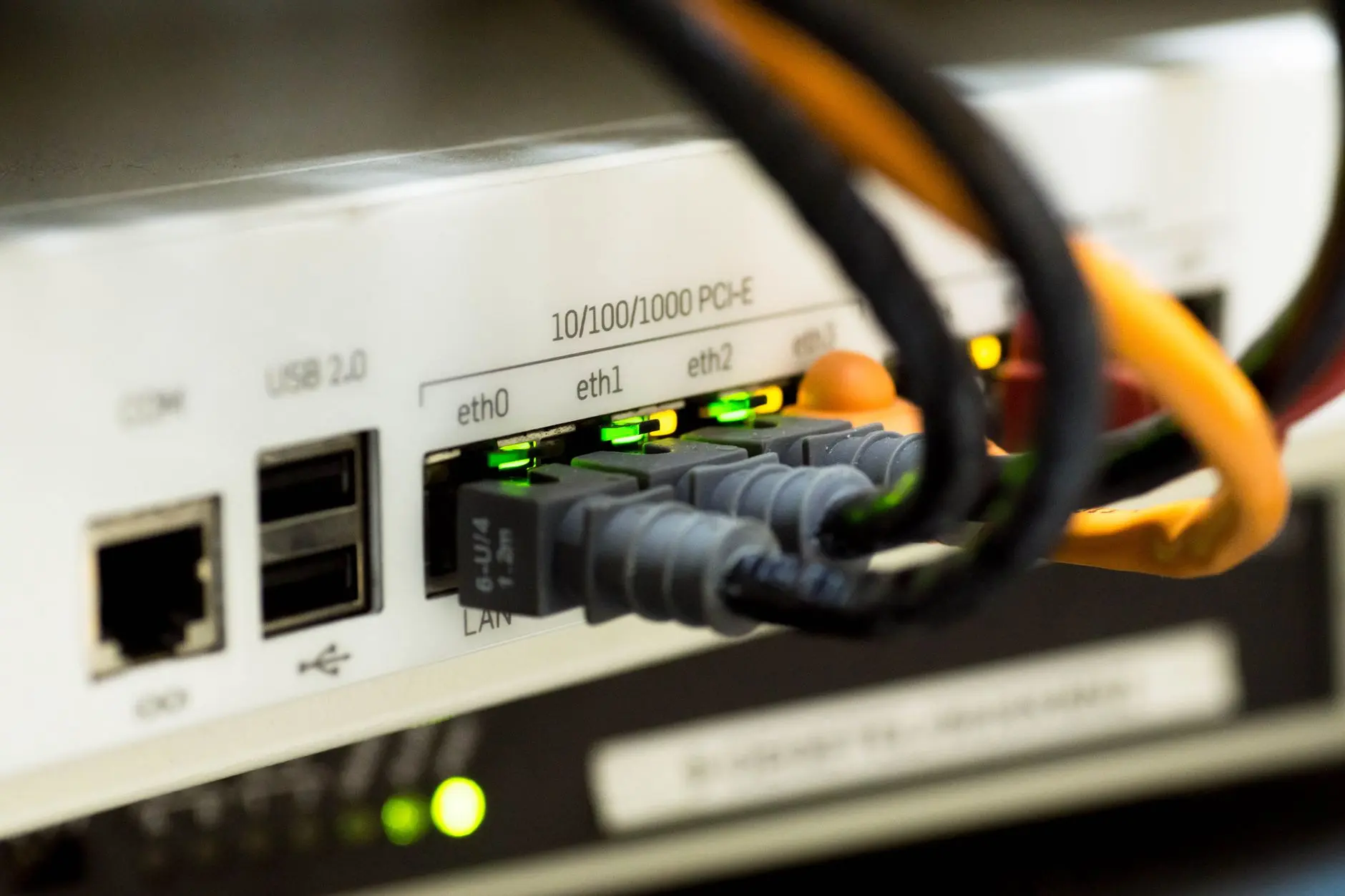 Cabos de rede conectados às portas de um switch com LEDs de atividade acesos