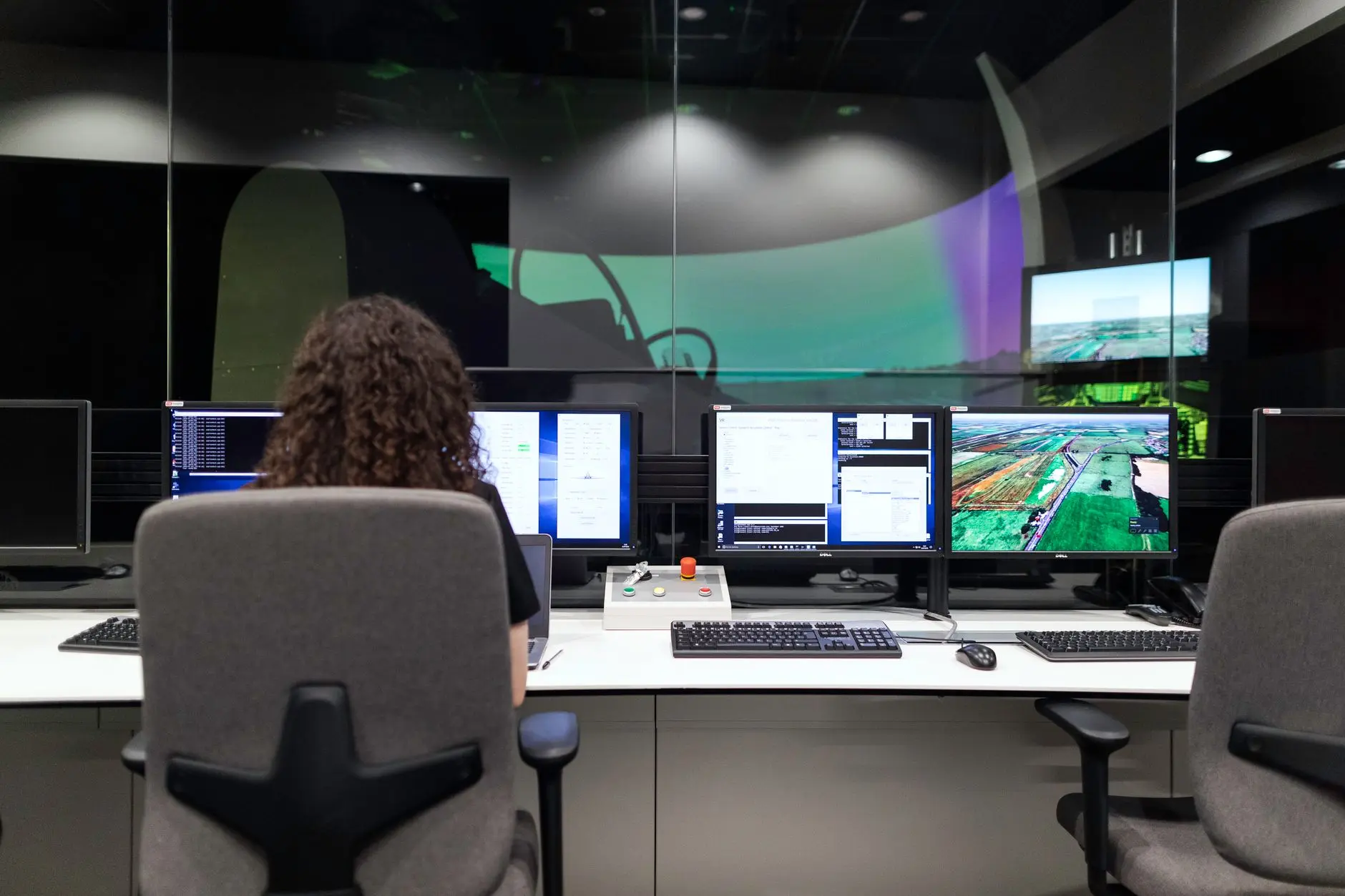 Engenheira acompanhando painéis de monitoramento em vários monitores em uma sala de controle