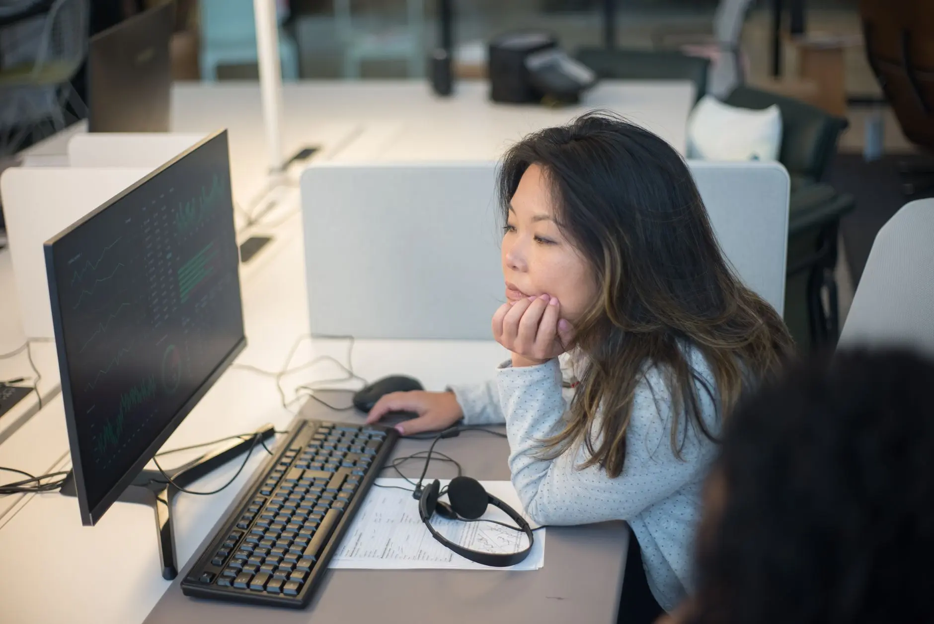 Analista acompanhando painéis de dados em um monitor no escritório