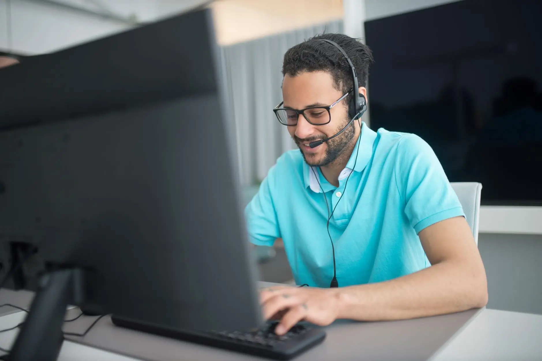 Técnico de suporte com fone de ouvido atendendo um chamado no computador