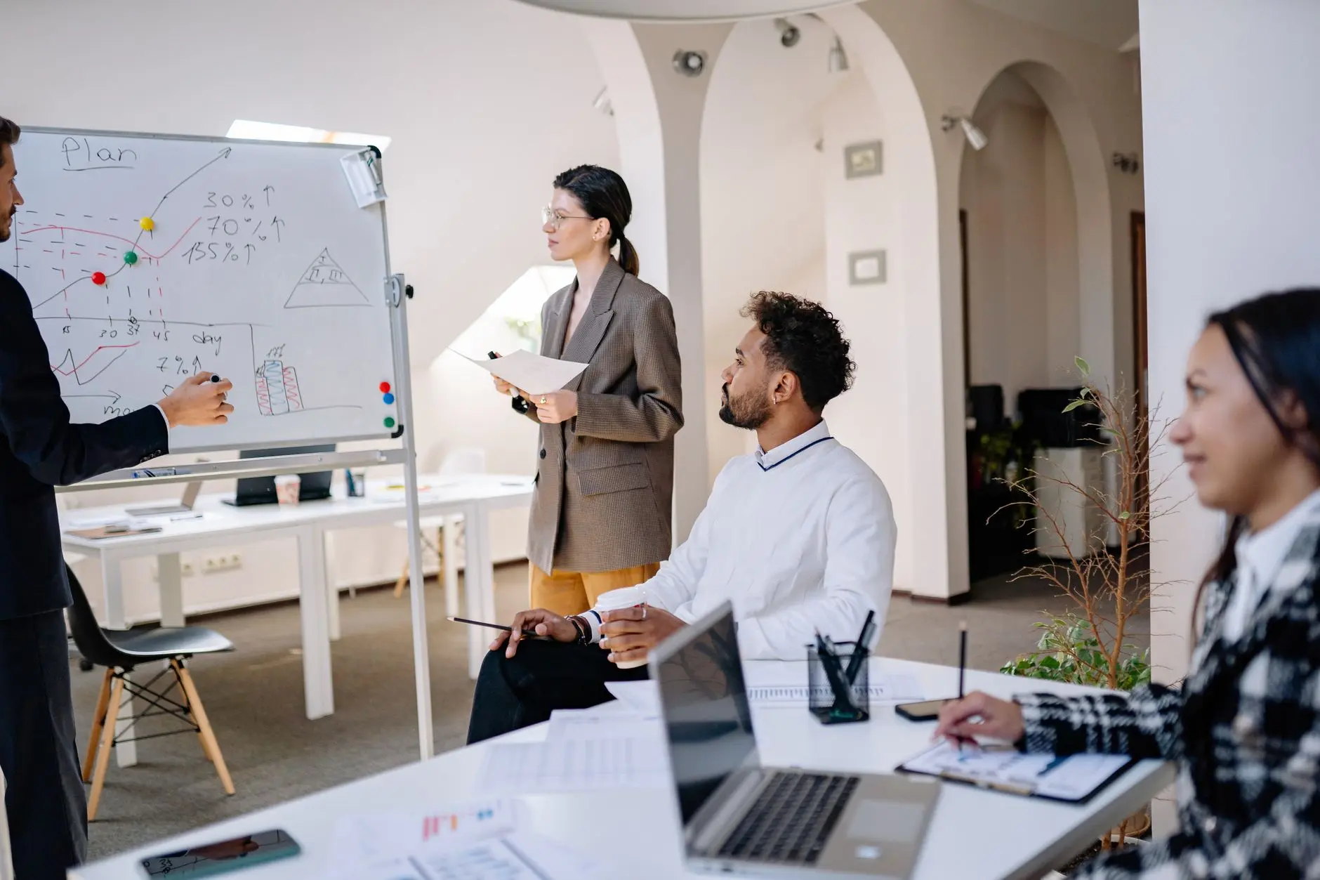 Colegas de trabalho discutindo ideias em frente a um quadro branco